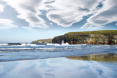 reflection of cliffs and clouds on a wet sandy ballybunion beach in irelandの写真素材