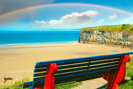 cliff walk bench overlooking the beautiful beach with rainbow in ballybunionの写真素材