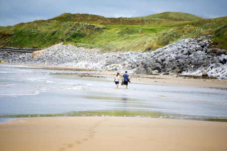 loving couple with dog paddeling on ballybunion beachの写真素材