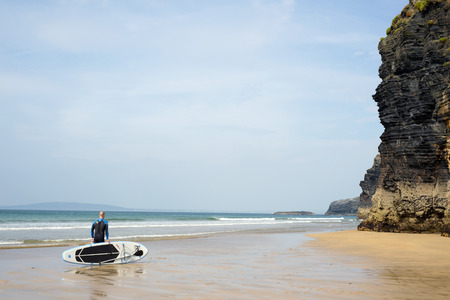 surfer standing with board on ballybunion beach in the wild atlantic wayの写真素材