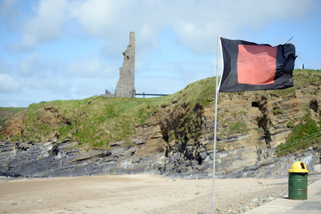 quicksilver flag flying beside surf school with ballybunion castle in backgroundの写真素材