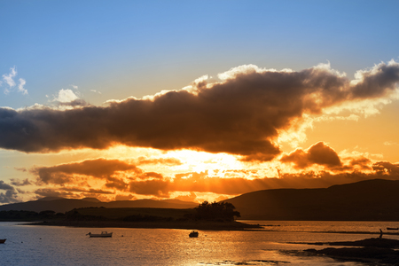 boats in a quiet bay with island near kenmare on the wild atlantic way ireland with an red sunsetの写真素材