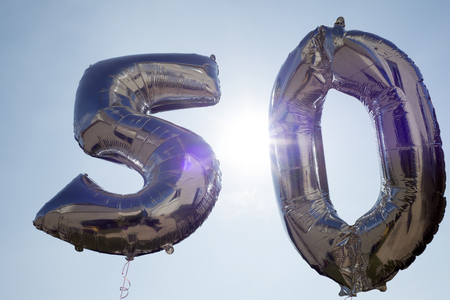 silver balloons for a 50th anniversary floating among the cloudsの写真素材