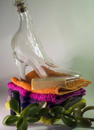 glass shoe and soap on facecloths of various shades with natural green plantの写真素材
