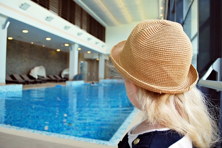 Little girl near swimming pool. Toddler girl in the pool looking sideways