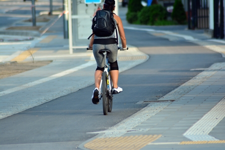 Back view of young woman riding on bike in the cityの写真素材