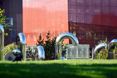 Public art installation in front modern building.Decorative stainless steel pipes