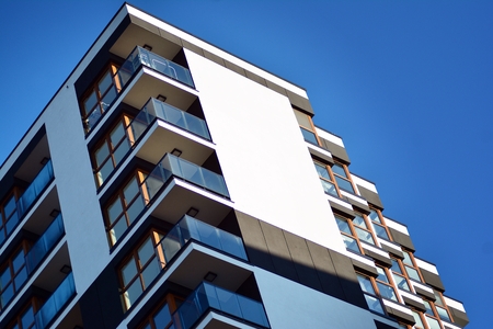 Fragment of a building with windows and balconies. Modern home with many flats.