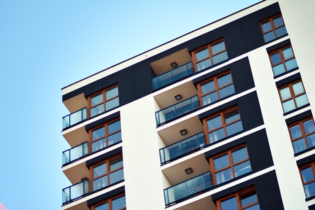 Fragment of a building with windows and balconies. Modern home with many flats.