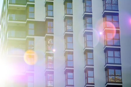 Fragment of a building with windows and balconies. Modern home with many flats.