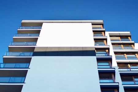 Fragment of a building with windows and balconies. Modern home with many flats.