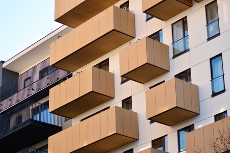 Fragment of a building with windows and balconies. Modern home with many flats.