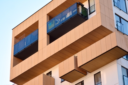 Fragment of a building with windows and balconies. Modern home with many flats.