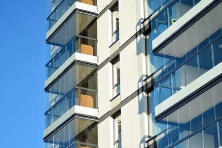 Fragment of a building with windows and balconies. Modern home with many flats.