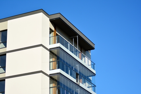 Fragment of a building with windows and balconies. Modern home with many flats.