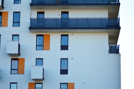 Fragment of a building with windows and balconies. Modern home with many flats.