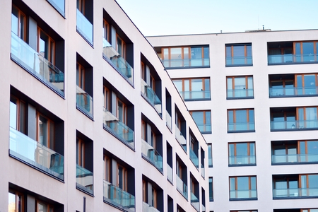 Fragment of a building with windows and balconies. Modern home with many flats.