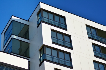 Fragment of a building with windows and balconies. Modern home with many flats.