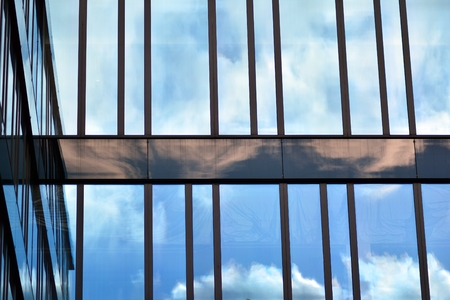 Modern building with reflected sky and cloud in glass windowの写真素材
