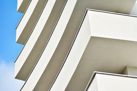Modern white building with balcony on a blue skyの写真素材