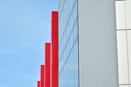 New office building in business center. Wall made of red steel and glass with blue sky.
