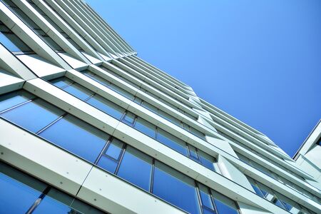 New office building in business center. Wall made of steel and glass with blue sky.