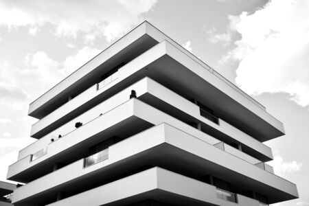Modern multi-storey luxury housing concept. Modern apartment building with dark sky and clouds. Dark shades of gray.の写真素材