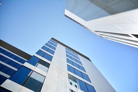 New office building in business center. Wall made of steel and glass with blue sky. Modern corporate...