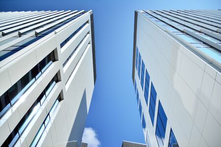 New office building in business center. Wall made of steel and glass with blue sky. Modern corporate...