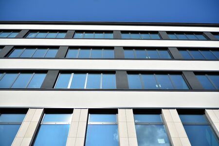 New office building in business center. Wall made of steel and glass with blue sky. Modern corporate...