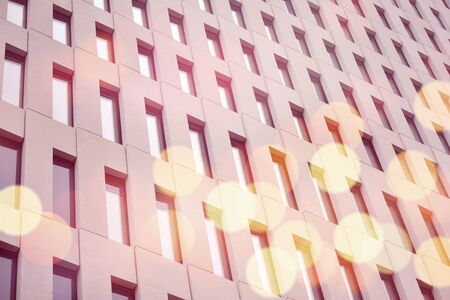 Modern office building detail. Perspective view of geometric angular concrete windows on the facade of a modernist brutalist style building surface with sunlight.の写真素材