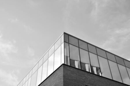 Curtain wall made of toned glass and steel constructions under sky. A fragment of a building. Black and white.の写真素材