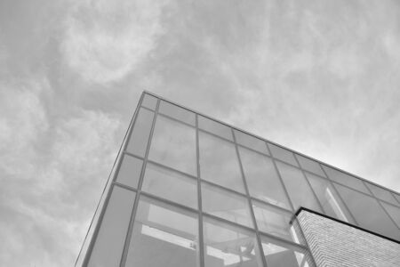 Curtain wall made of toned glass and steel constructions under sky. A fragment of a building. Black and white.の写真素材