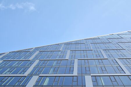 Modern office building wall made of steel and glass with blue sky