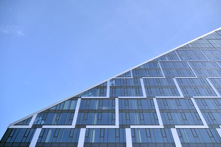 Modern office building wall made of steel and glass with blue sky