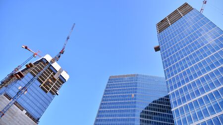 New modern office skyscraper being built in a city. Architectural facade building during construction with of glass elements finished and in concrete.の写真素材
