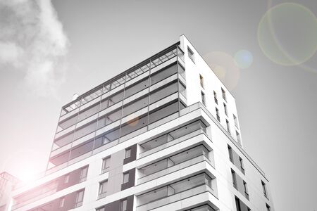 Detail of modern residential flat apartment building exterior. Fragment of new luxury house and home complex. Glass surface with sunlight. Black and white.の写真素材