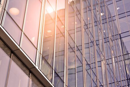 Sun rays light effects on urban buildings in sunset. Modern office building detail, glass surface...