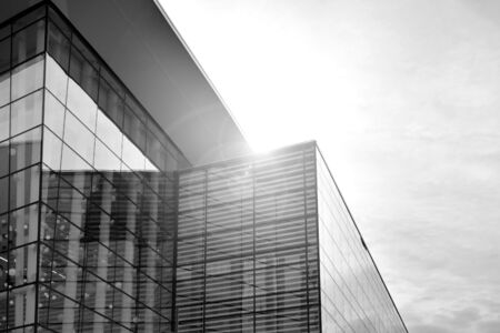 Sun rays light effects on urban buildings in sunset. Modern office building detail, glass surface with sunlight. Business background. Black and white.の写真素材