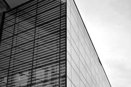 Sun rays light effects on urban buildings in sunset. Modern office building detail, glass surface with sunlight. Business background. Black and white.の写真素材