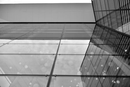 Sun rays light effects on urban buildings in sunset. Modern office building detail, glass surface with sunlight. Business background. Black and white.の写真素材
