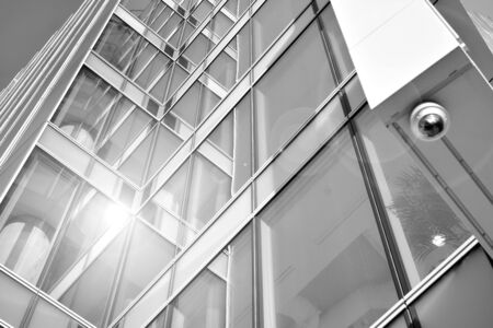 Sun rays light effects on urban buildings in sunset. Modern office building detail, glass surface with sunlight. Business background. Black and white.の写真素材