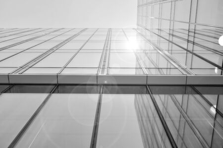 Sun rays light effects on urban buildings in sunset. Modern office building detail, glass surface with sunlight. Business background. Black and white.の写真素材