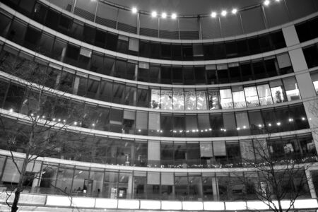 Night architecture - building with glass facade. Business district. Concept of economics, financial. Photo of commercial office building exterior. Abstract image of office building. Black and white.の写真素材