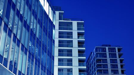 Night architecture - building with glass facade. Blue color of night lights. Modern building in...