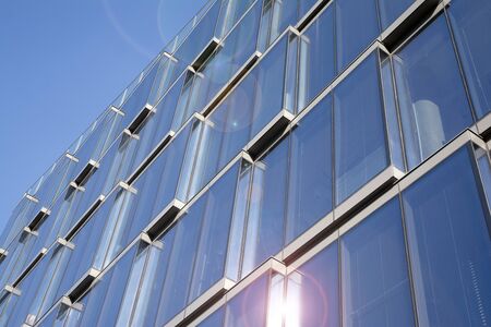 Office building glass facades on a bright sunny day with sunbeams in the blue sky. Abstract view of...