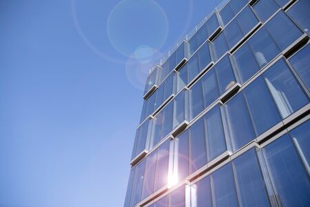 Office building glass facades on a bright sunny day with sunbeams in the blue sky. Abstract view of...