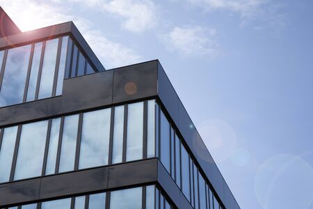 Office building glass facades on a bright sunny day with sunbeams in the blue sky. Abstract view of...