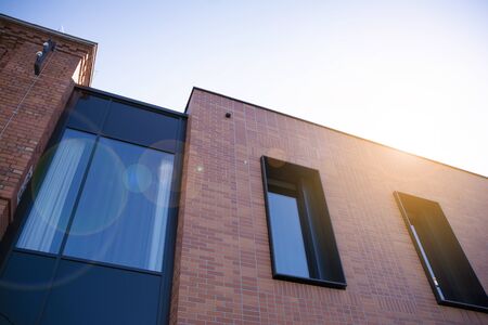 Office building glass facades on a bright sunny day with sunbeams in the blue sky. Abstract view of a skyscraper with sunlightの写真素材