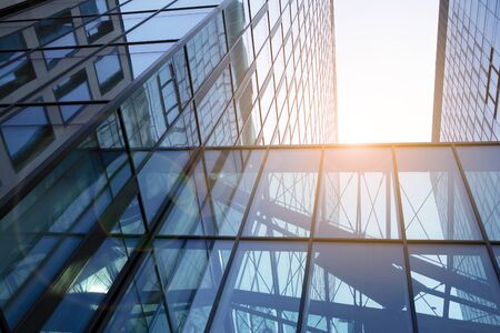 Modern architecture with sun ray. Glass facade on a bright sunny day with sunbeams in the blue sky.